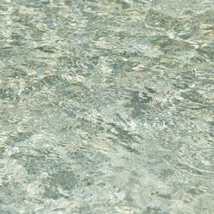 A close-up photograph of the natural stone surface, featuring a mix of green and gray shades with small black and white speckles throughout, creating a beautiful and unique pattern.