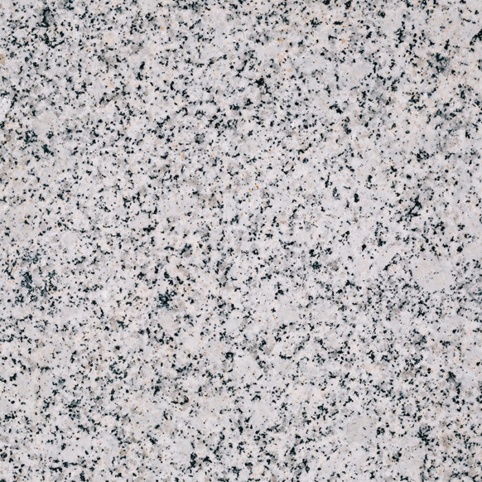 A White Granite Slab With Grey And Black Speckles And Patches.