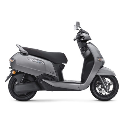 The scooter features a modern and futuristic design with sharp lines, LED lighting, and a large windscreen. It has a compact body, alloy wheels, and a digital instrument cluster. The scooter is powered by an electric motor and has a removable Lithium-Ion battery, offering a range of up to 75 km per charge. It also has regenerative braking, smartphone connectivity, and a reverse assist feature. The alt text highlights the scooter's electric powertrain, advanced features, and distinctive appearance.