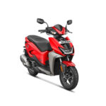 The scooter features a modern and minimalist design with a clean silhouette, sharp lines, and LED lighting. It has a compact body, with a digital instrument cluster, disc brakes, and alloy wheels. The scooter is powered by an electric motor and has a removable Lithium-Ion battery, offering a range of up to 75 km per charge. It also has regenerative braking for enhanced energy efficiency. The alt text highlights the scooter's contemporary design, electric powertrain, and eco-friendly features.