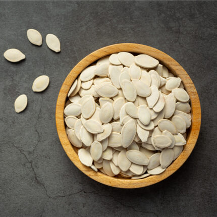 The pumpkin seeds are small and flat with a teardrop shape, and have a light brown color with a slightly glossy surface. The image captures the appearance of pumpkin seeds, a popular snack and ingredient in various dishes known for their mild, nutty flavor and crunchy texture. The alt text conveys the small, flat teardrop shape, light brown color, and glossy surface of pumpkin seeds. Pumpkin seeds can be eaten on their own as a snack or used as a topping for salads, yogurt, or oatmeal.