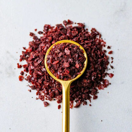 The powder is deep red in color and has a fine texture. The image captures the appearance of Sumac, a spice commonly used in Middle Eastern cuisine. The alt text conveys the deep red color and fine texture of Sumac powder. Sumac has a tangy and slightly sour taste, and is often used as a seasoning for meat, fish, vegetables, and salads.