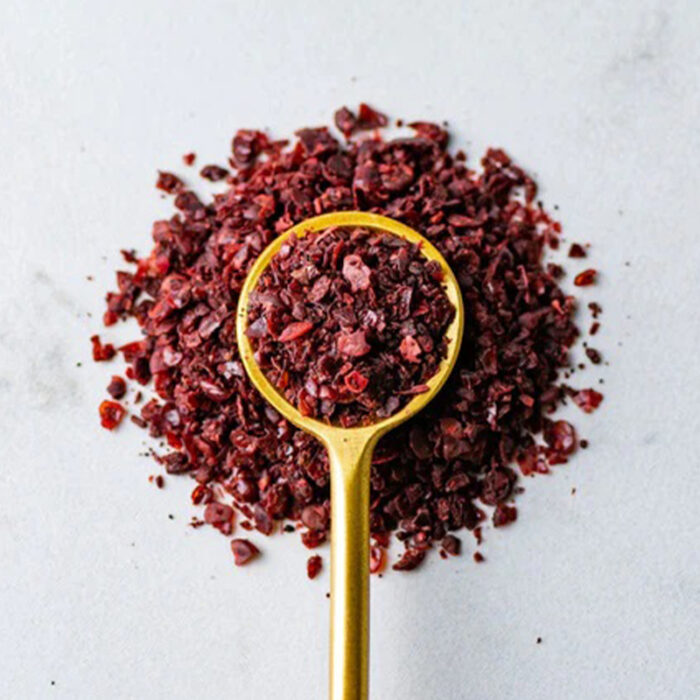 The Powder Is Deep Red In Color And Has A Fine Texture. The Image Captures The Appearance Of Sumac, A Spice Commonly Used In Middle Eastern Cuisine. The Alt Text Conveys The Deep Red Color And Fine Texture Of Sumac Powder. Sumac Has A Tangy And Slightly Sour Taste, And Is Often Used As A Seasoning For Meat, Fish, Vegetables, And Salads.